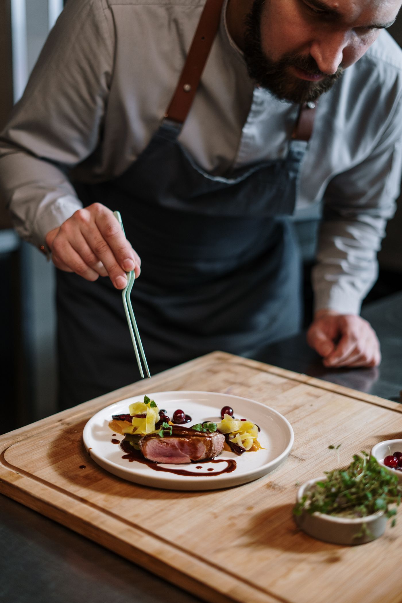 Cuisinier qui dresse une assiette sur une planche en bois